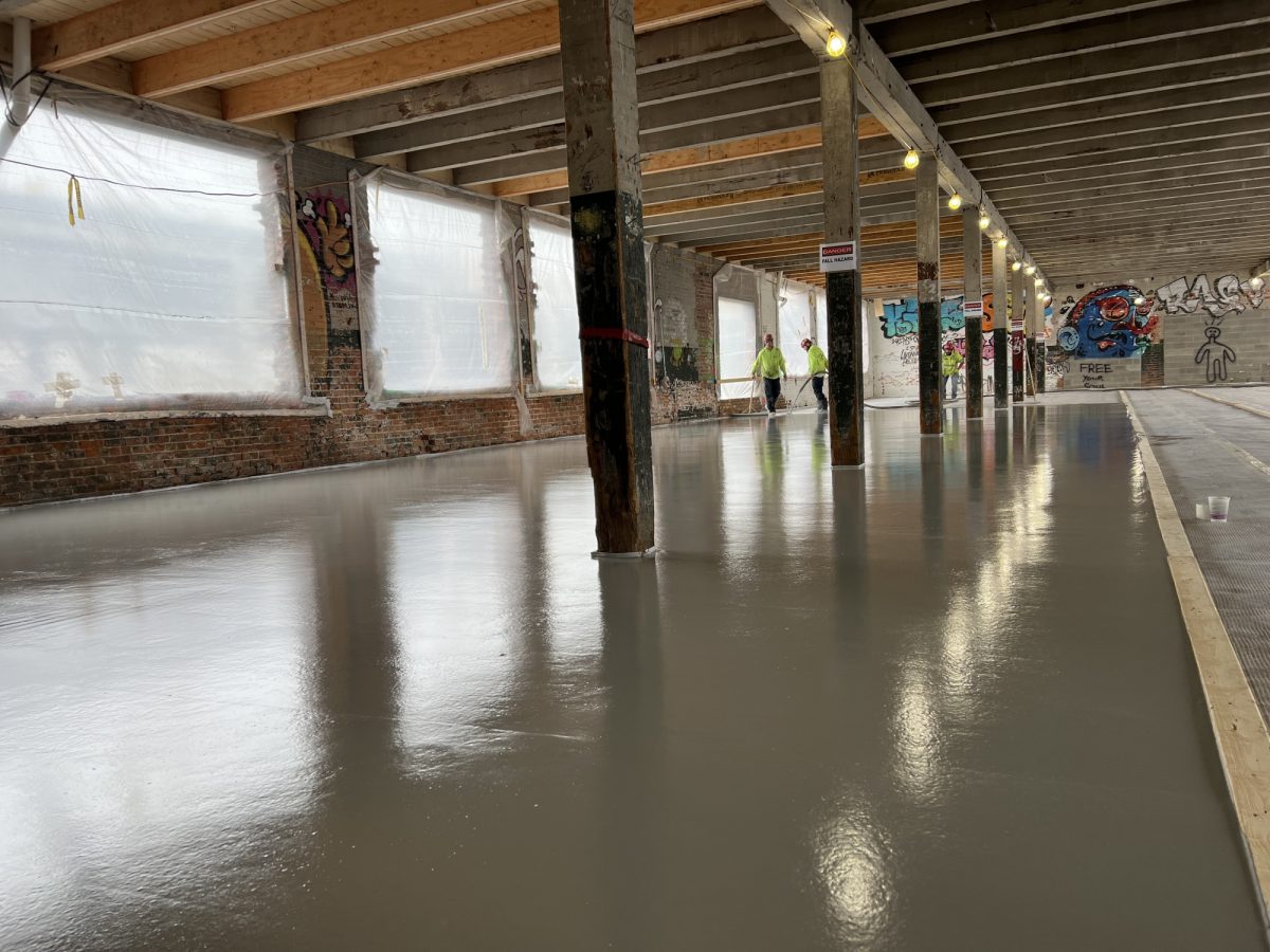 Construction workers in hi vis pouring underlayments for renovation